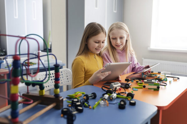 two-young-girls-using-tablets-electronic-parts-build-drone